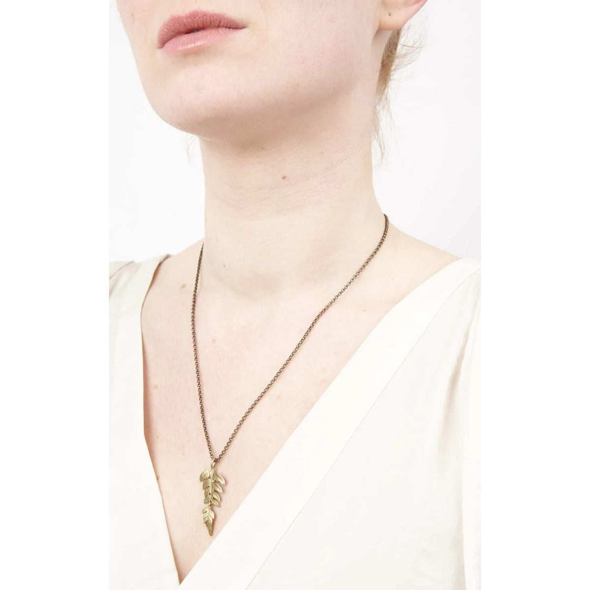 Necklace with a leaf pendant worn by a person on a white background