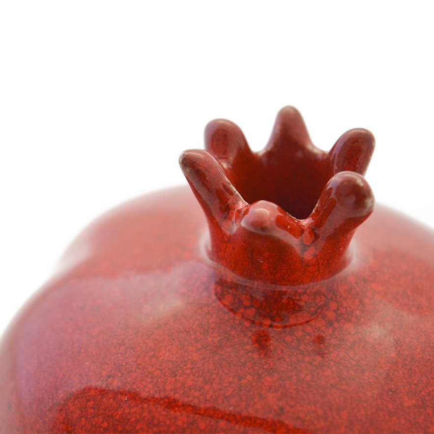 Close-up of a red ceramic object with a textured surface on a white background