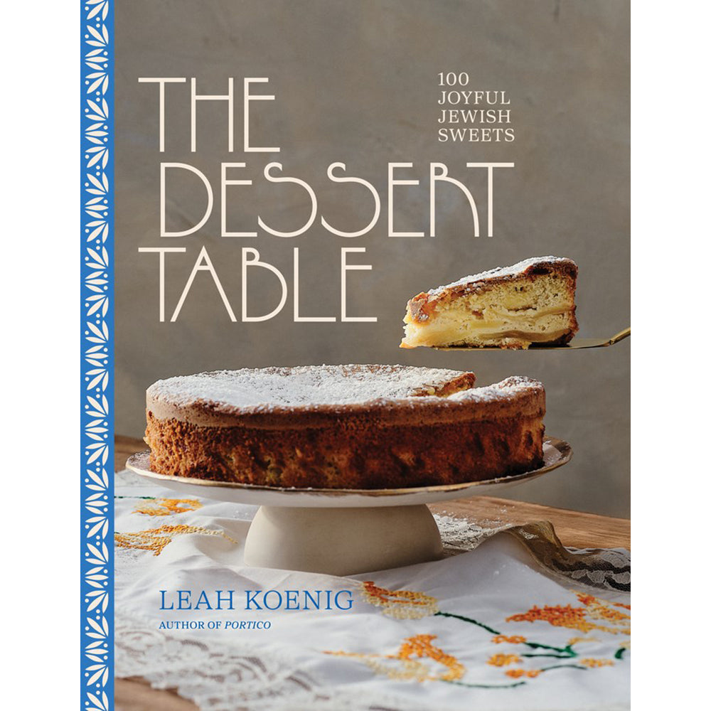 The front cover of the book 'The Dessert Table' by Leah Koenig, featuring a large photograph of a cake on a stand with a slice lifted on a fork, set against a warm gray background with a blue patterned border on the left.