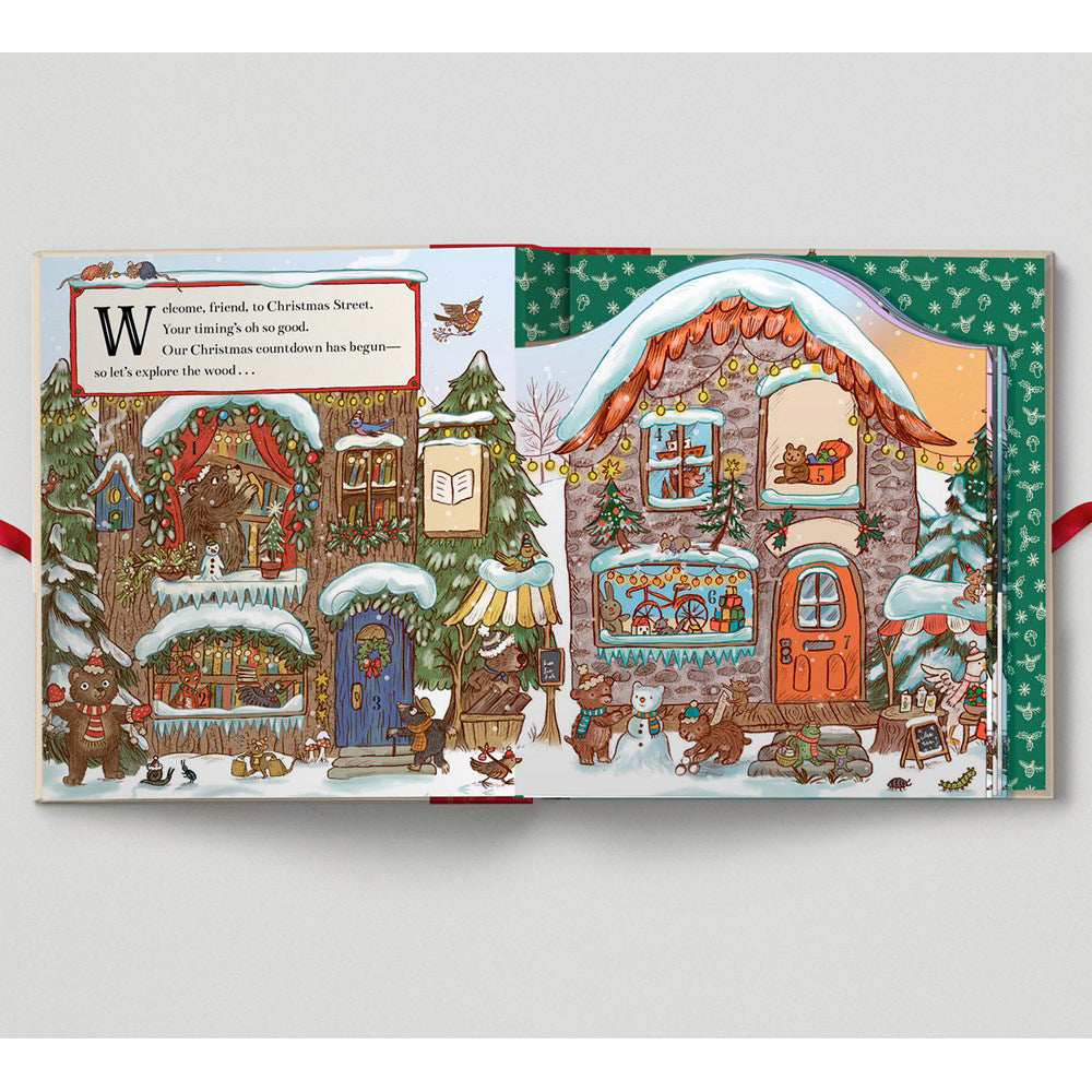 Illustrated Christmas scene with houses and snowy landscape on a book page.