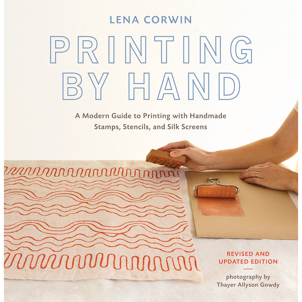 Book cover of 'Printing by Hand' by Lena Corwin, featuring a hand using a wooden stamp to create orange wavy lines on beige fabric, alongside a silk screen roller. The title is displayed in large blue outlined letters against a clean white background.