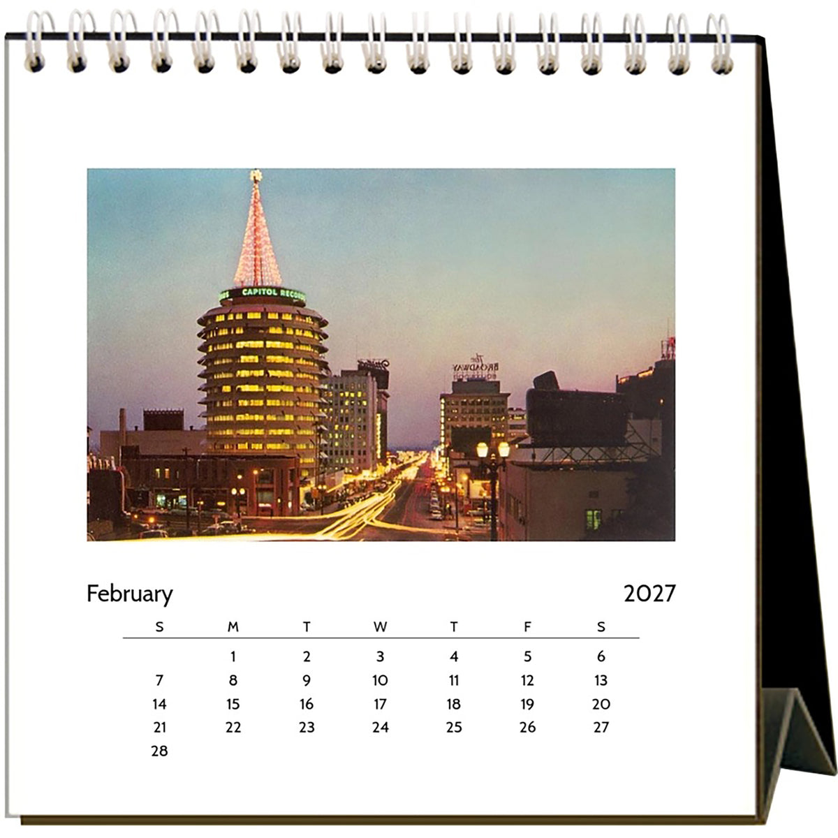 A spiral-bound desk calendar page showing a city photograph with the heading February 2027 and a days-of-the-week schedule at the bottom.