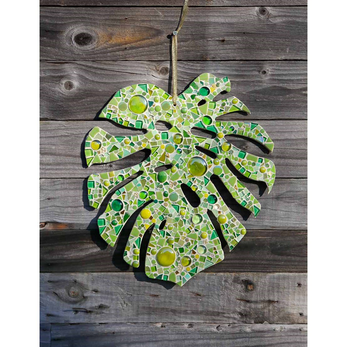 Decorative mosaic leaf wall art on a wooden background
