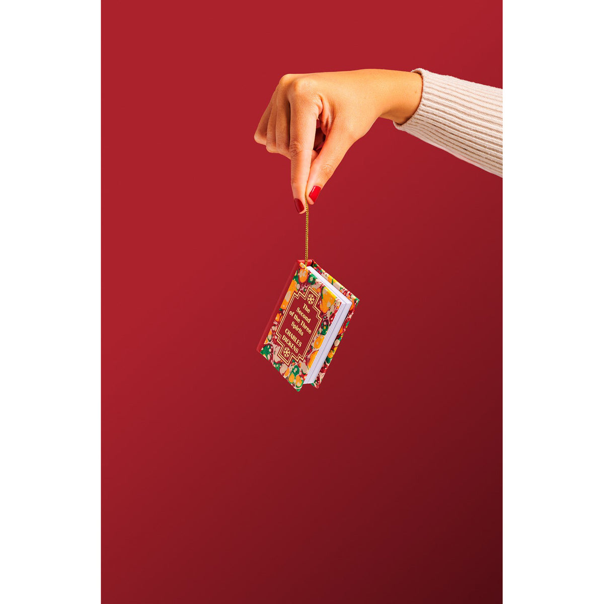 Hand holding a small book ornament