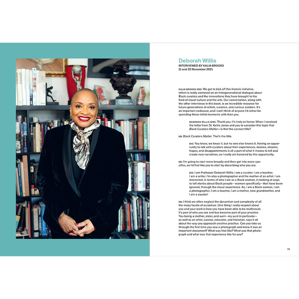 Woman in a black suit standing in front of a bookshelf with text on the right side.