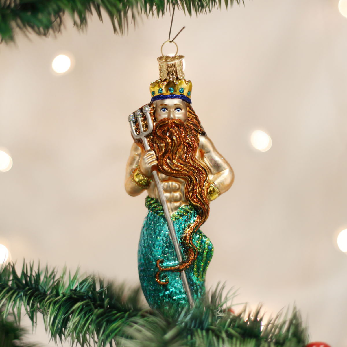 Mermaid ornament with a crown and trident on a Christmas tree.