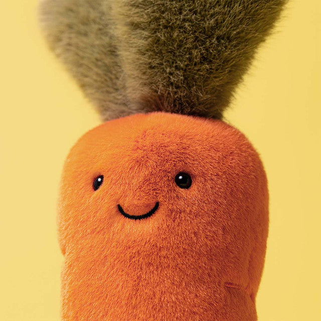 Stuffed toy carrot with a smiling face on a white background