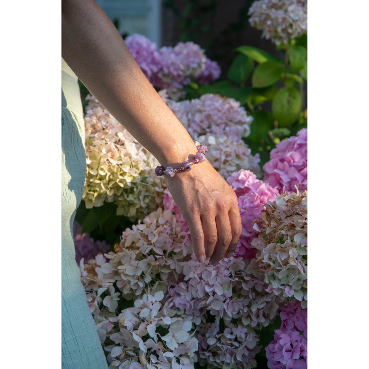 Hand wearing a bracelet with flowers in the background