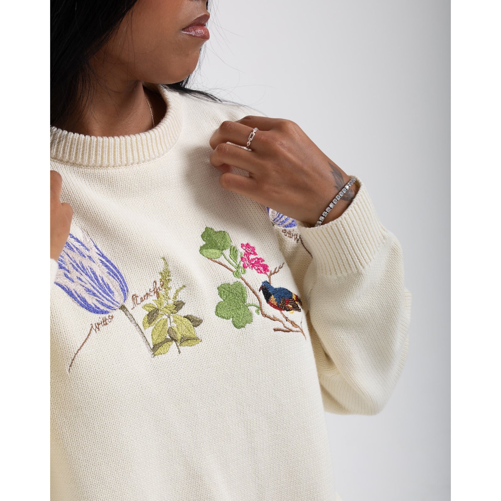 Cream sweater with floral and bird embroidery on a white background