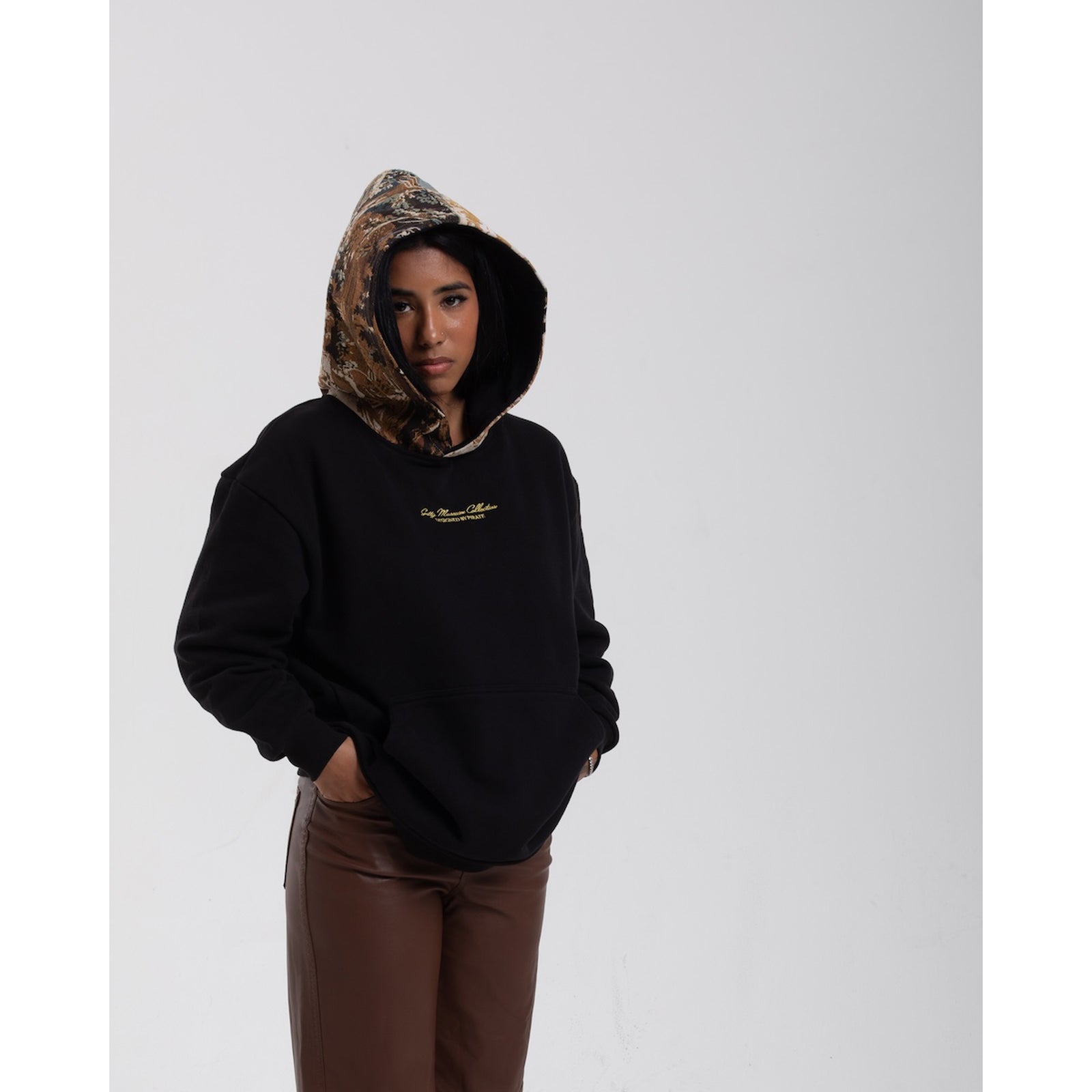 Person wearing a black hoodie with a camouflage hood on a white background