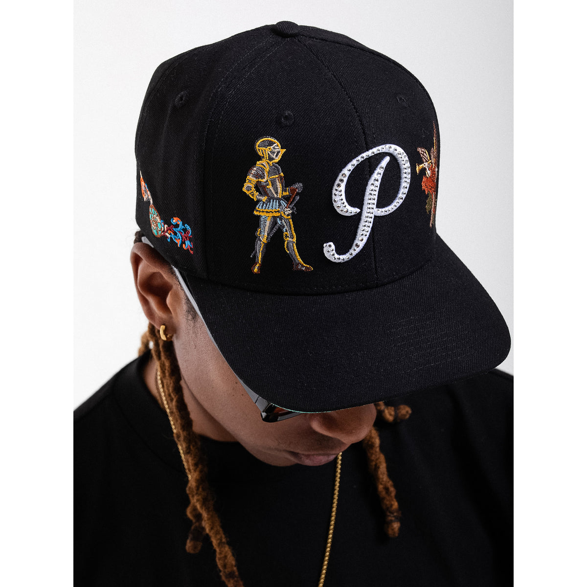 Black cap with embroidered designs and a large 'P' on a white background