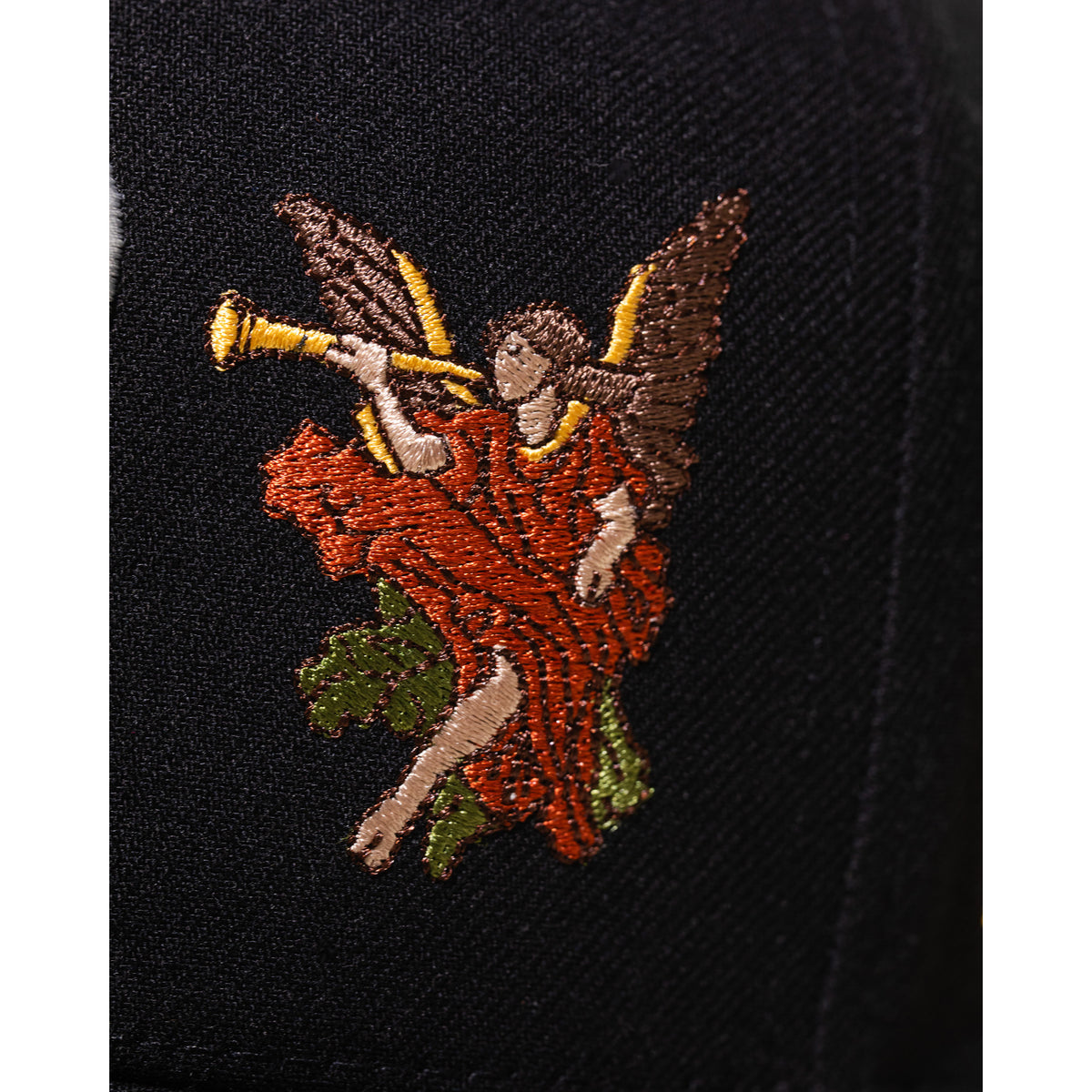 Embroidered angel with a trumpet on black fabric