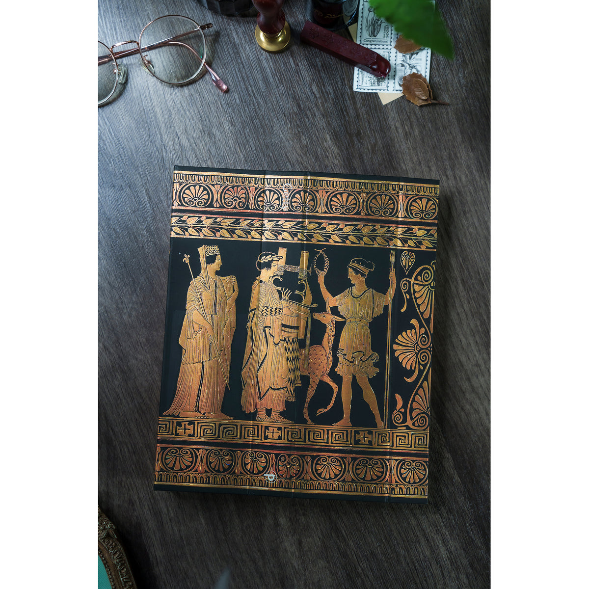 Decorative notebook with ancient Greek design on a wooden surface