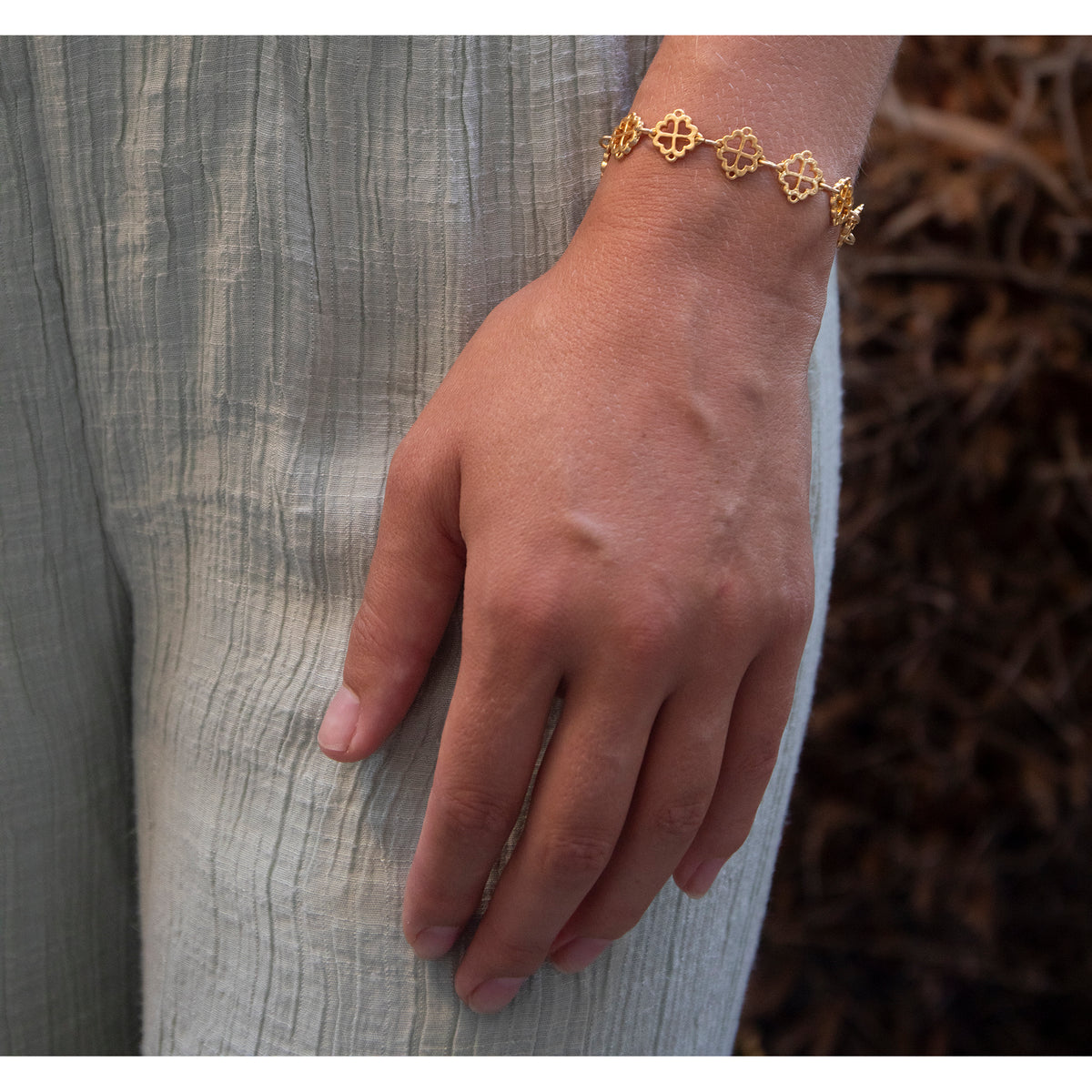 Hand wearing a gold bracelet with a textured background
