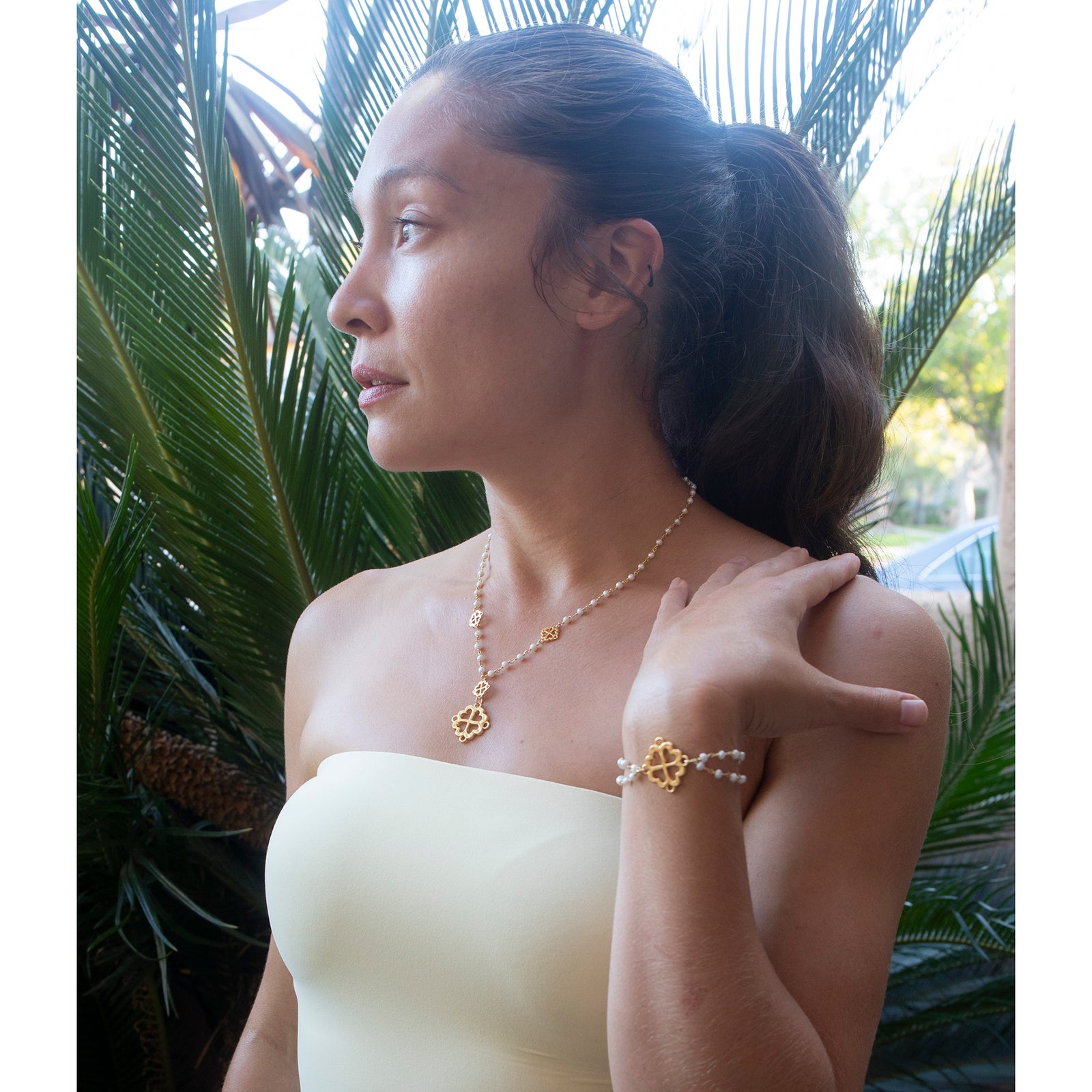 Gold necklace with clover-shaped pendants on a white background