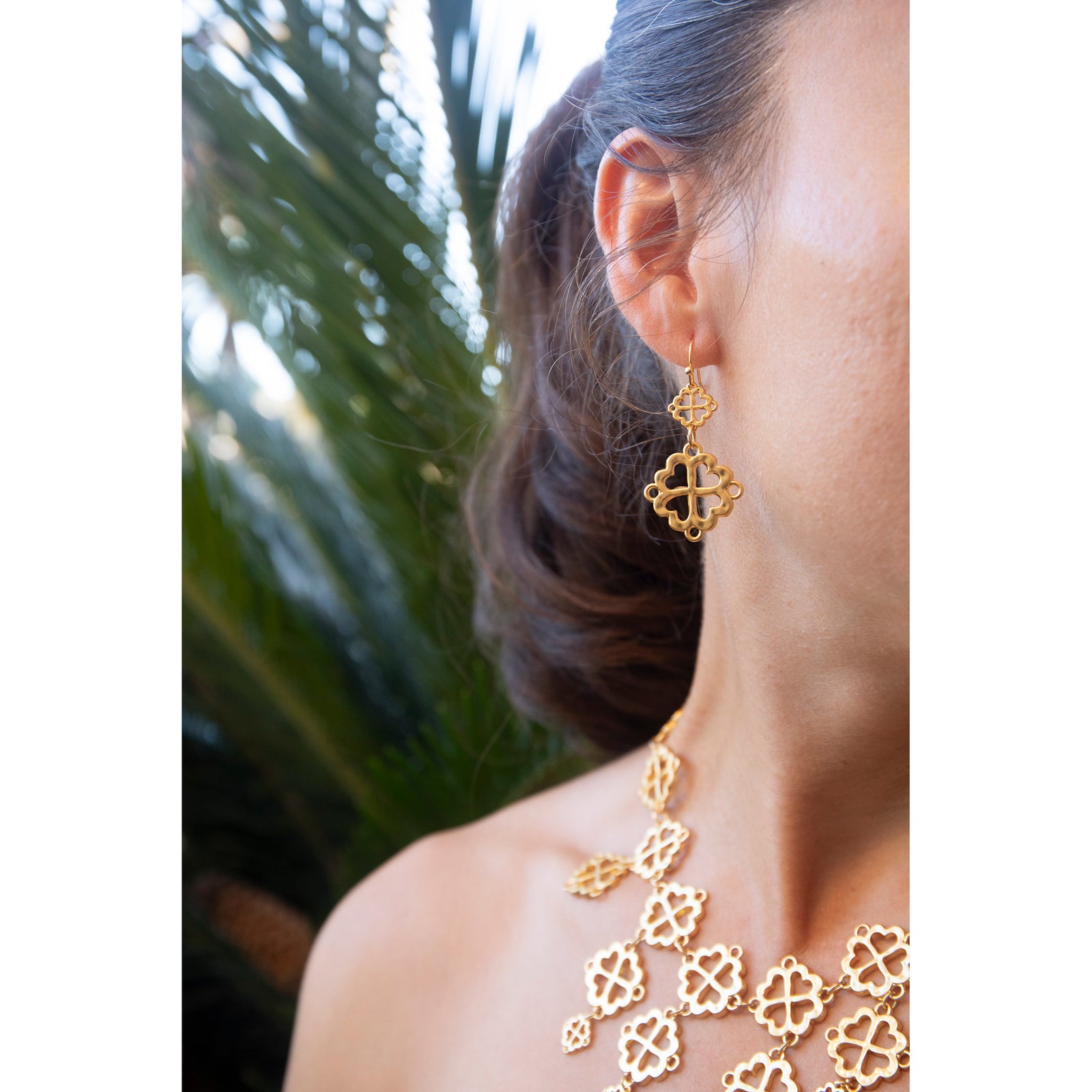 Gold earrings with clover-like designs on a white background