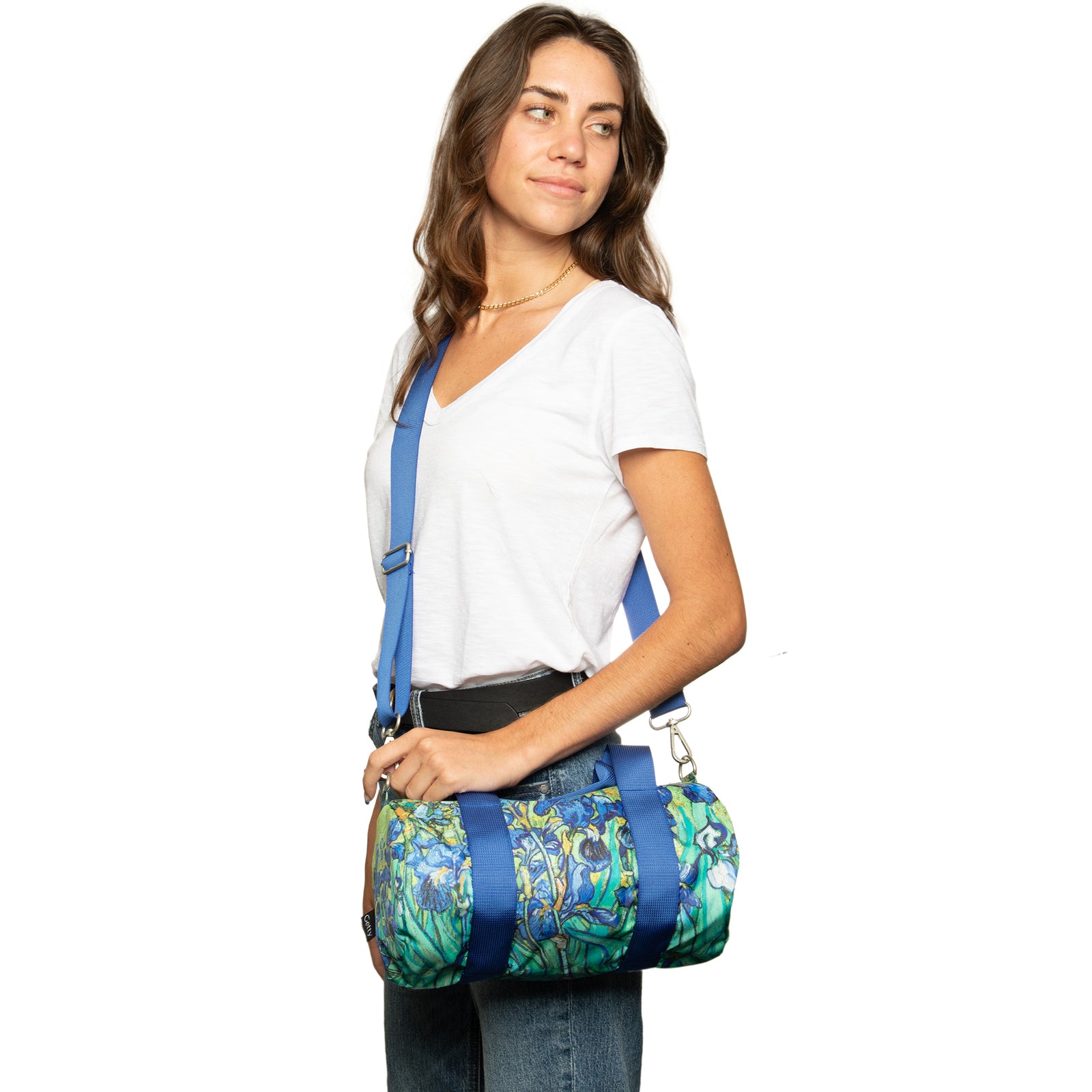 A person holding a medium-sized weekender bag featuring a vibrant pattern inspired by Van Gogh's Irises painting.