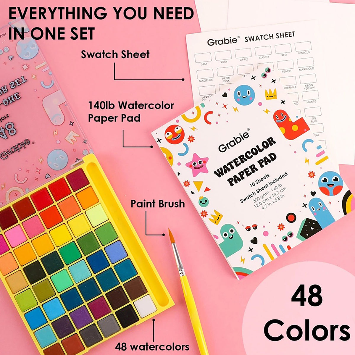 Artistic set with watercolor paper pad, paint brush, and swatch sheet on a pink background