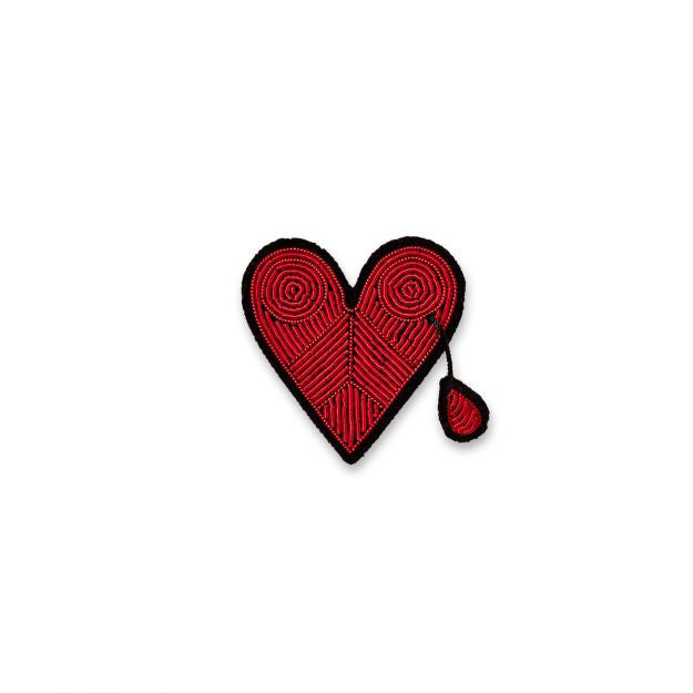 Red heart-shaped brooch with black border on a white background