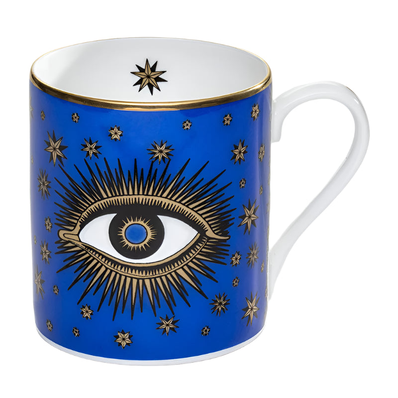 A blue fine bone china mug with a white and gold eye design, surrounded by star patterns, and a white handle.