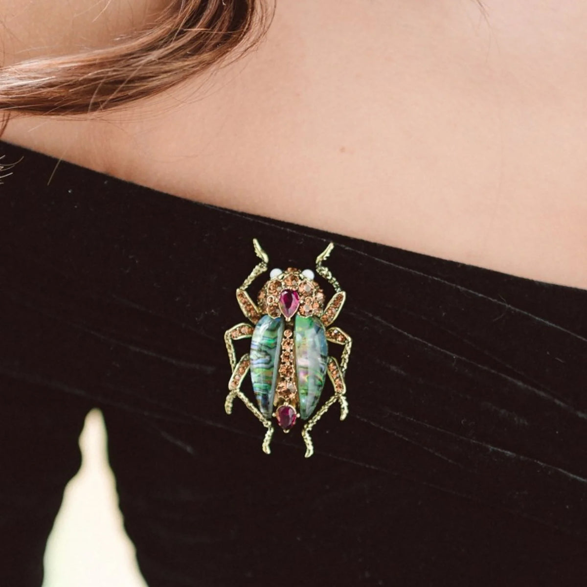 Decorative brooch shaped like a beetle on a black garment
