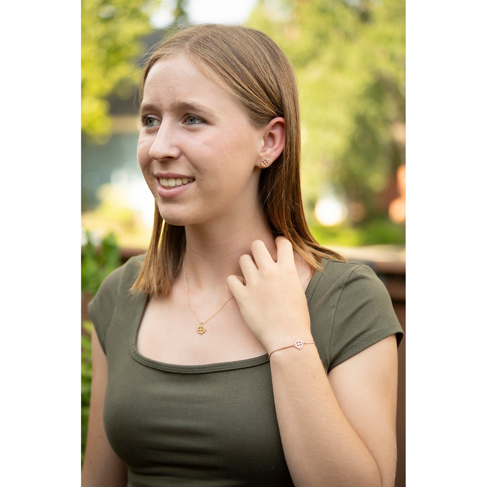 A pair of gold square charms with a four-leaf clover design and heart cutouts, displayed on a clean white background.