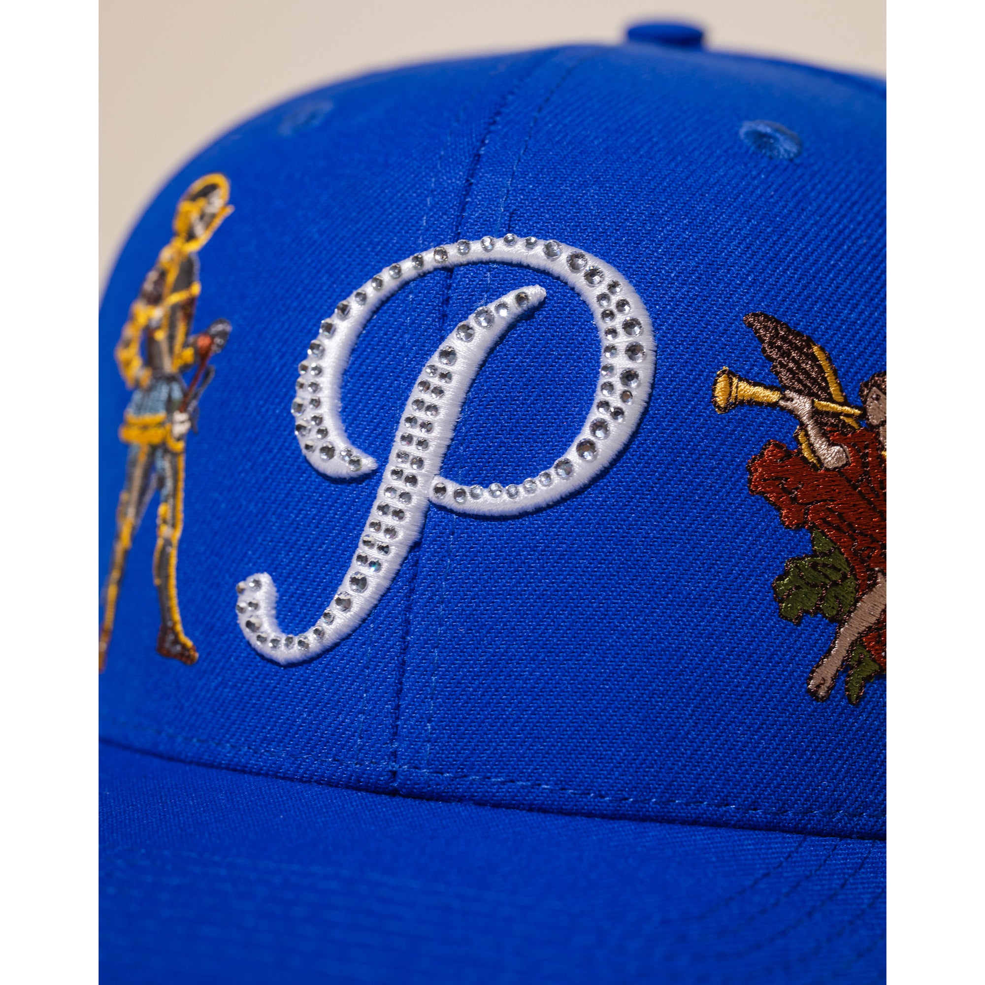 Blue cap with embroidered designs on a white background