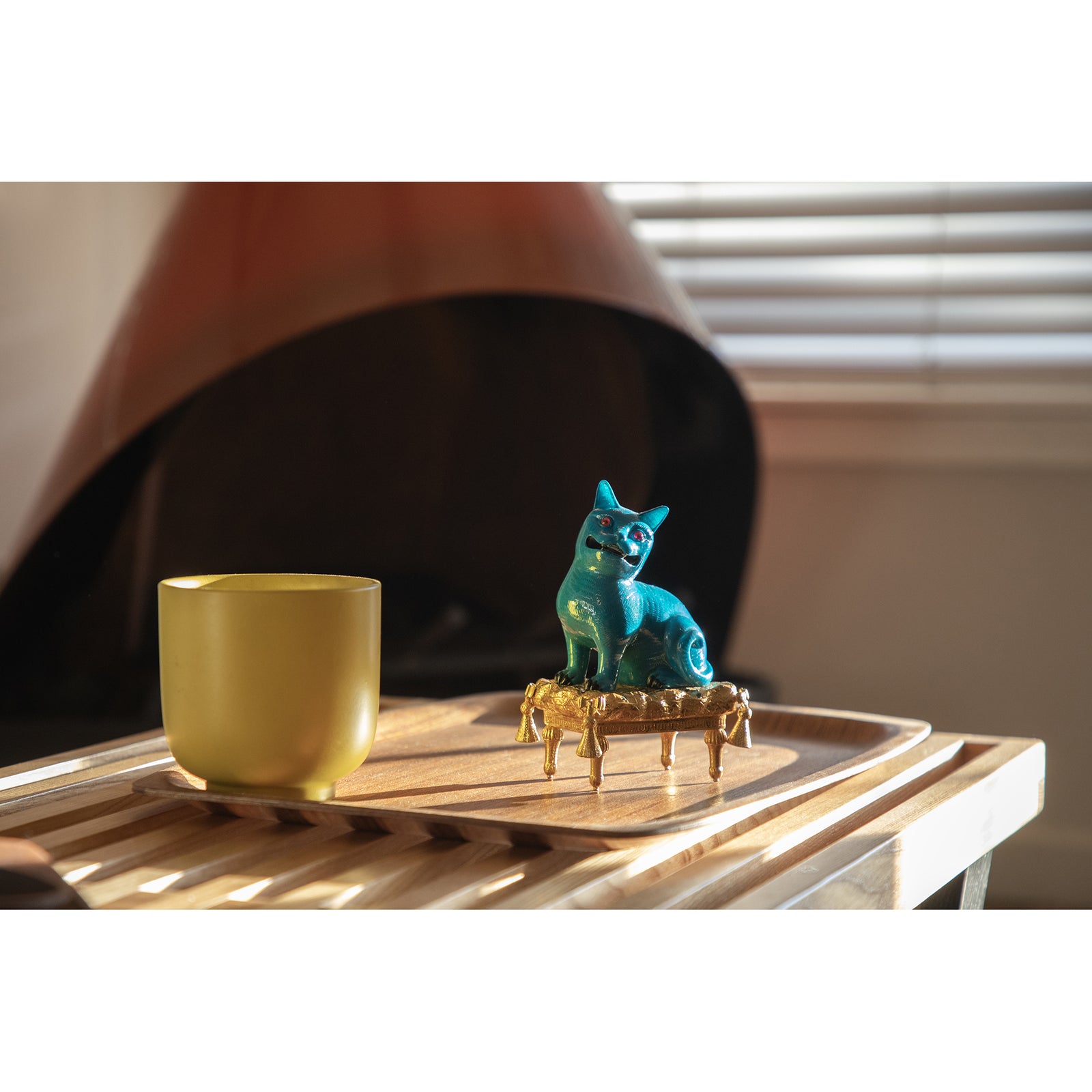 Blue cat figurine on a gold pedestal against a white background