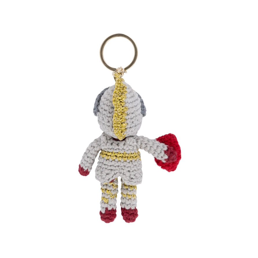 Crocheted keychain in the shape of a character with red shoes, gold accents, and a white background