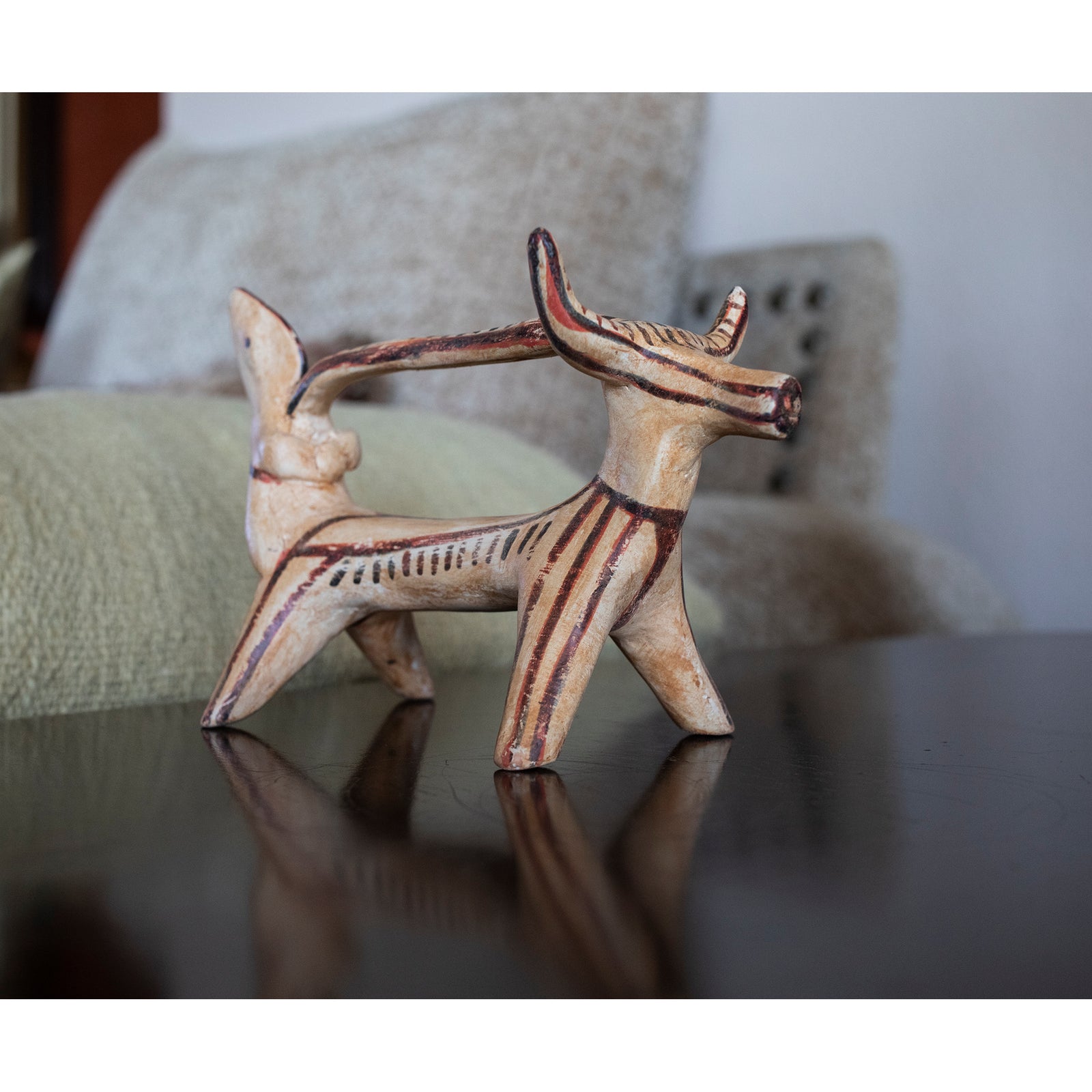 Ceramic figurine of a creature with large horns on a white background