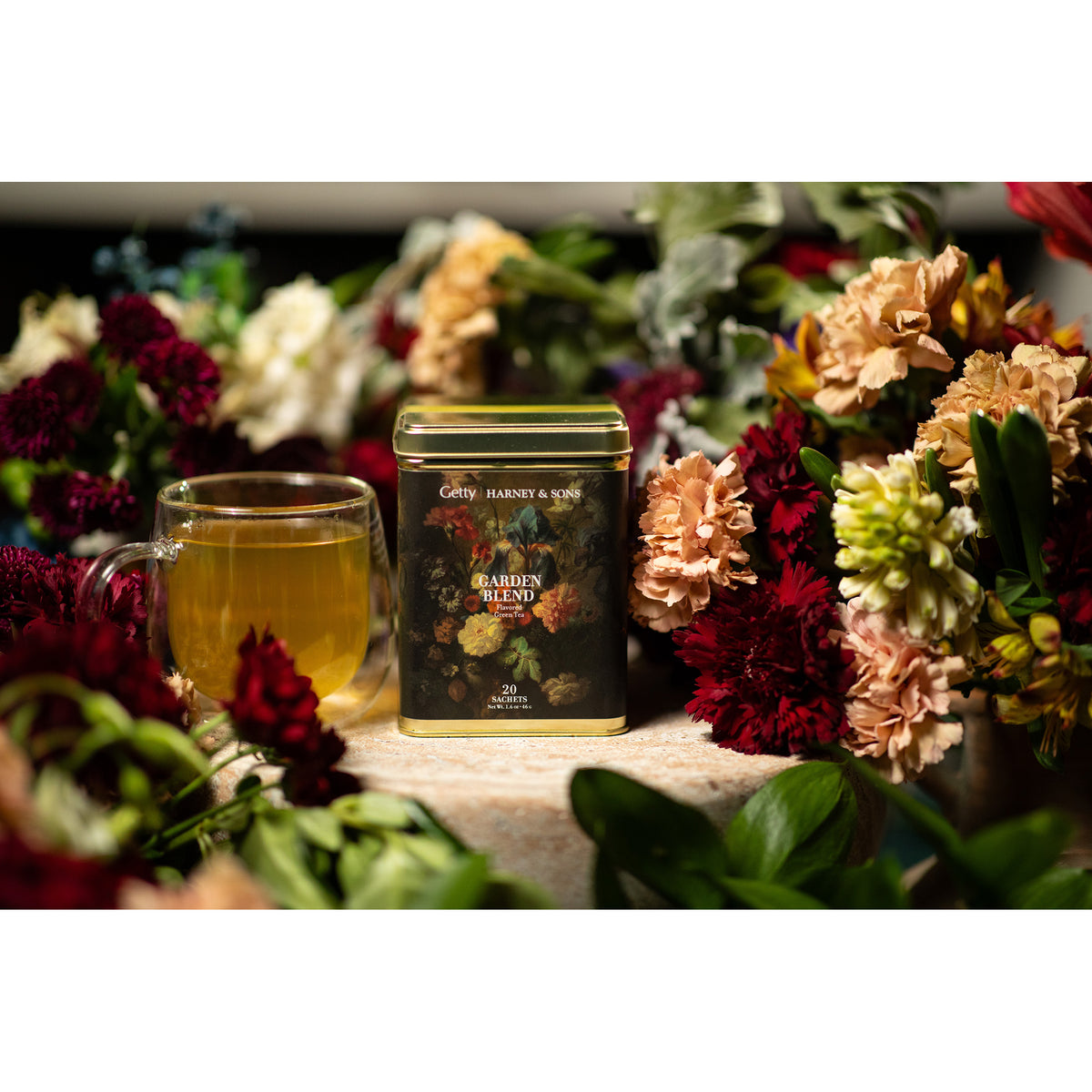 Tea canister with a cup of tea surrounded by flowers on a white background