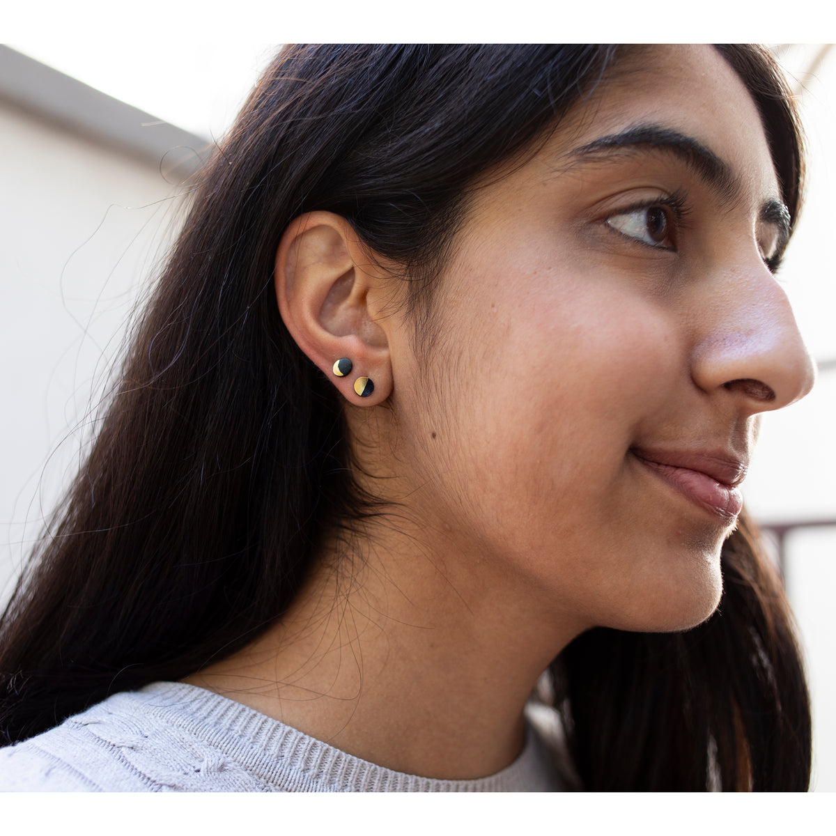 Close-up of a woman wearing gold earrings with a blurred background