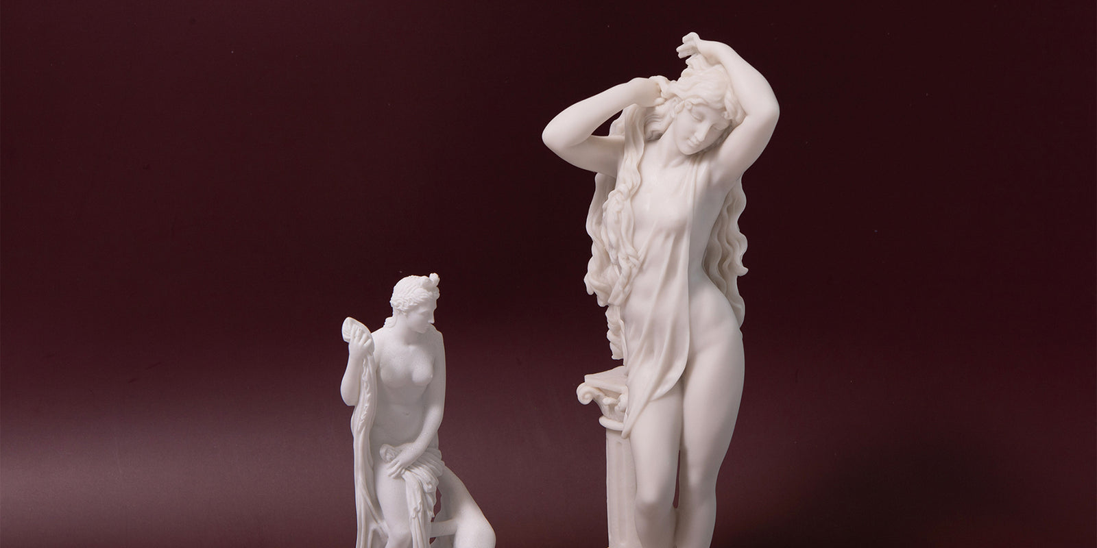 White marble sculpture of a nude figure on a dark red background