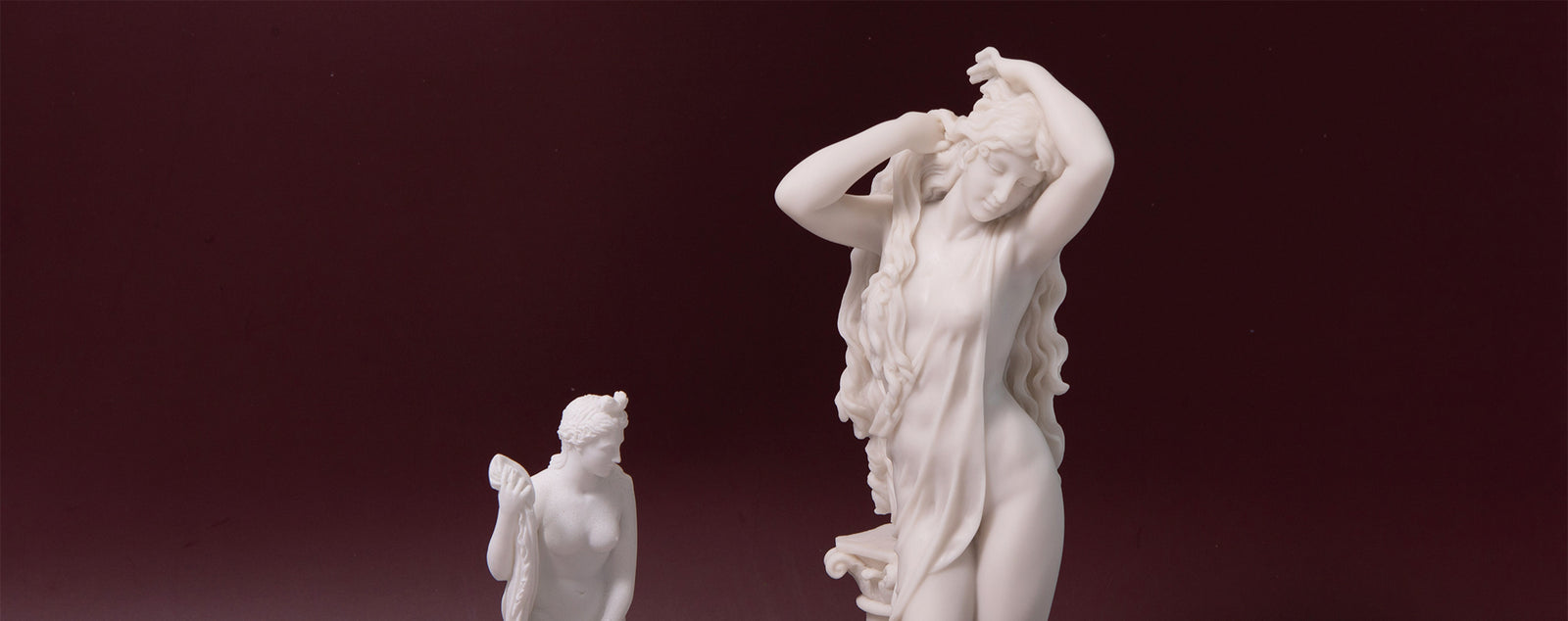 White marble statue of a nude figure on a dark red background