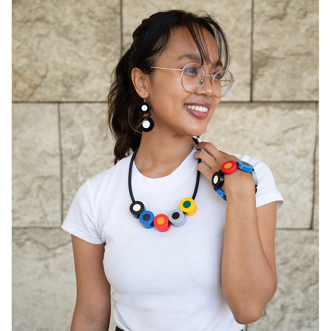 A necklace with a black cord featuring a series of colorful circular beads in red, blue, green, yellow, and black, arranged in a line.