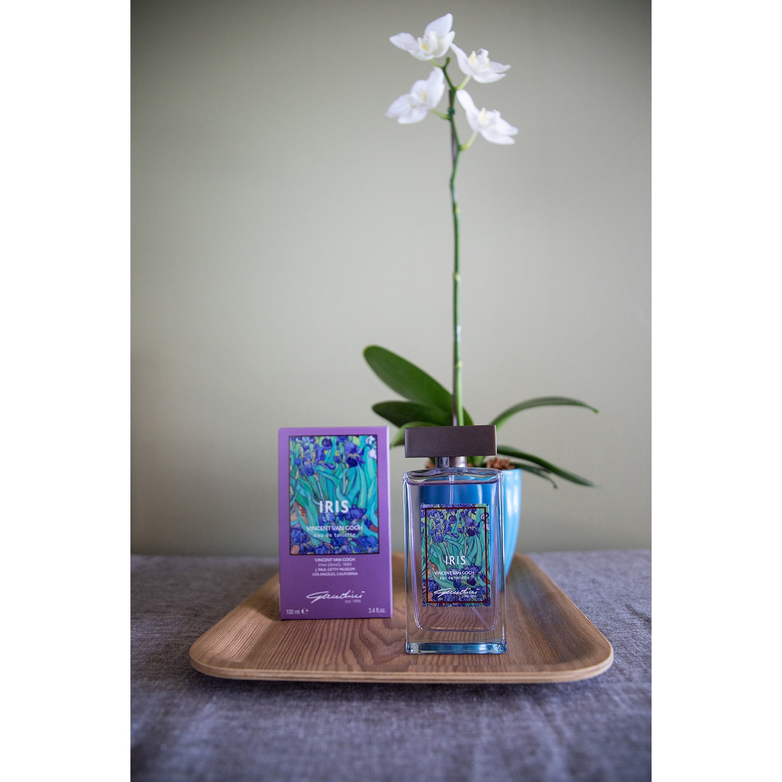 A bottle of Iris Eau de Toilette with a purple label featuring an image of Van Gogh's painting 'Irises', alongside its packaging box.