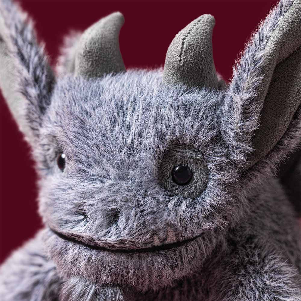 A plush gray gargoyle toy with small horns, folded wings, and a soft furry texture, photographed on a clean white background.