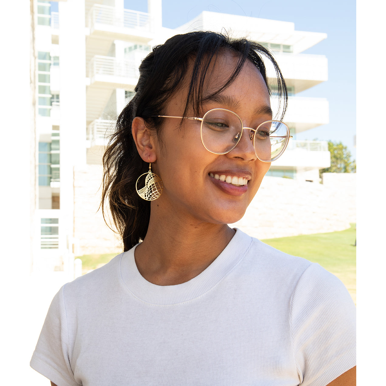 A pair of hoop earrings with a geometric curve design, available in gold or silver-tone.