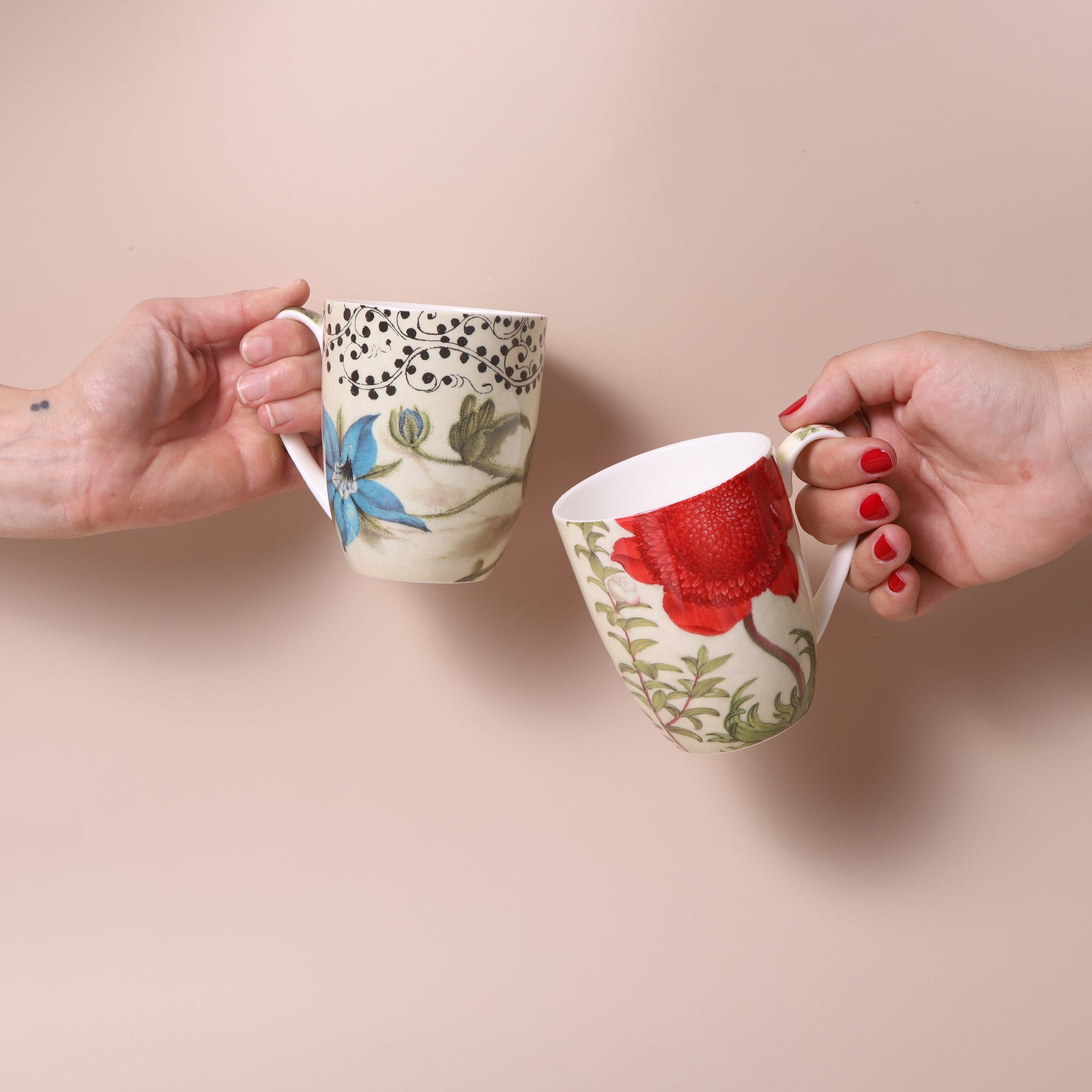 Two decorative mugs in a box with floral and butterfly design, placed on a white background.