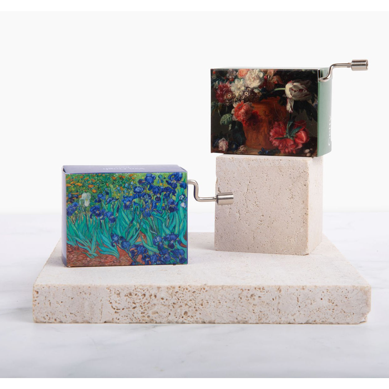 A music box with a printed detail from Vincent van Gogh's painting 'Irises' on its exterior. The music box has a hand crank on the side and displays the artwork in vibrant colors.