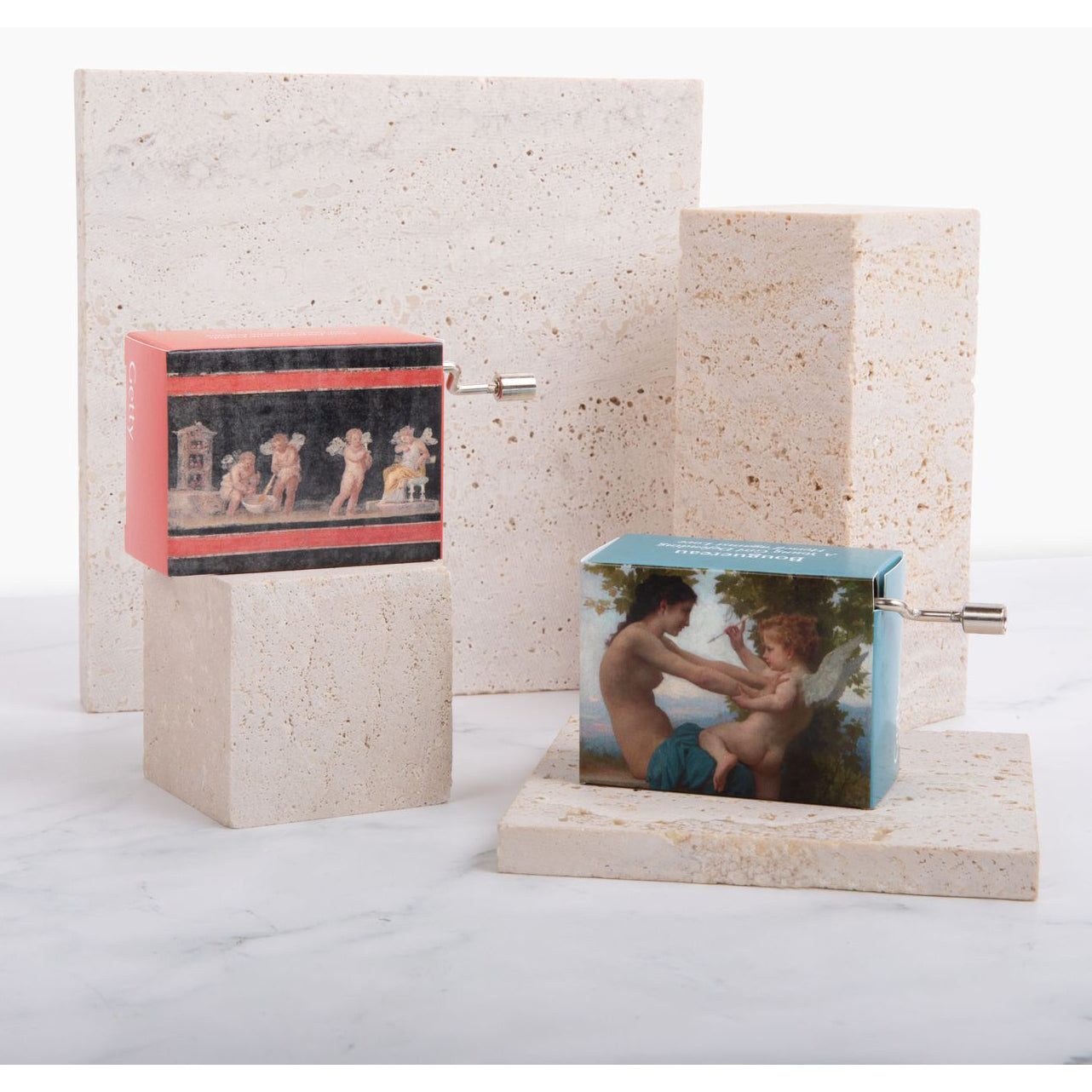 A small music box with a print of ancient Roman fresco depicting Cupids and Psyche on the front, with a hand crank on the side.