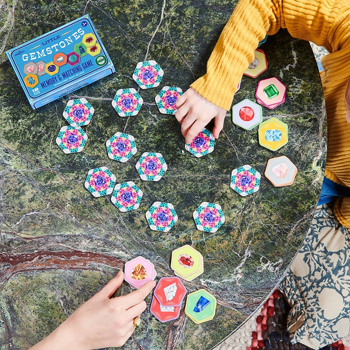 Children playing with a gemstone matching game on a marble table