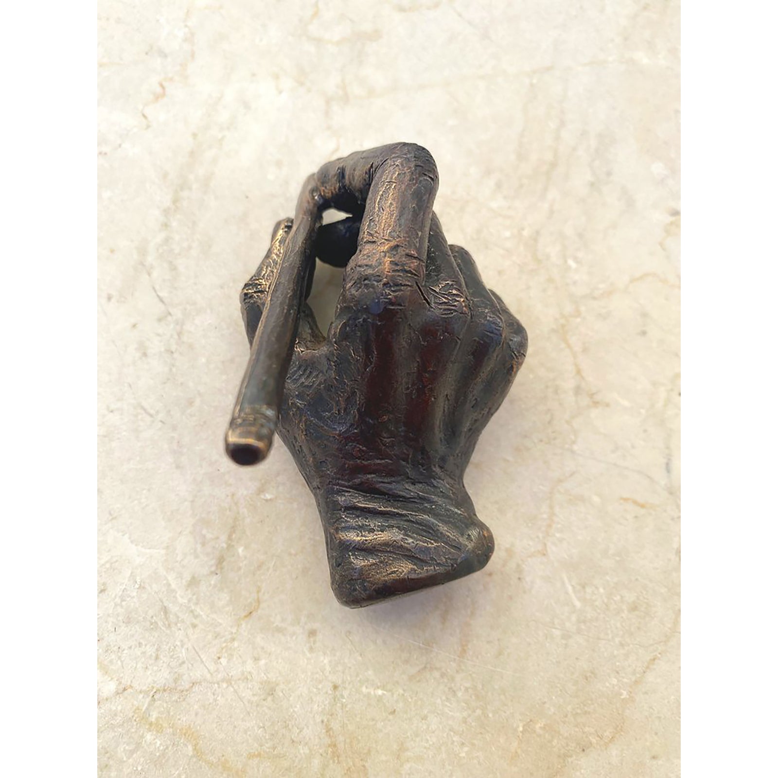 A bronze sculpture of a hand holding a pencil, symbolizing the art of writing or drawing.