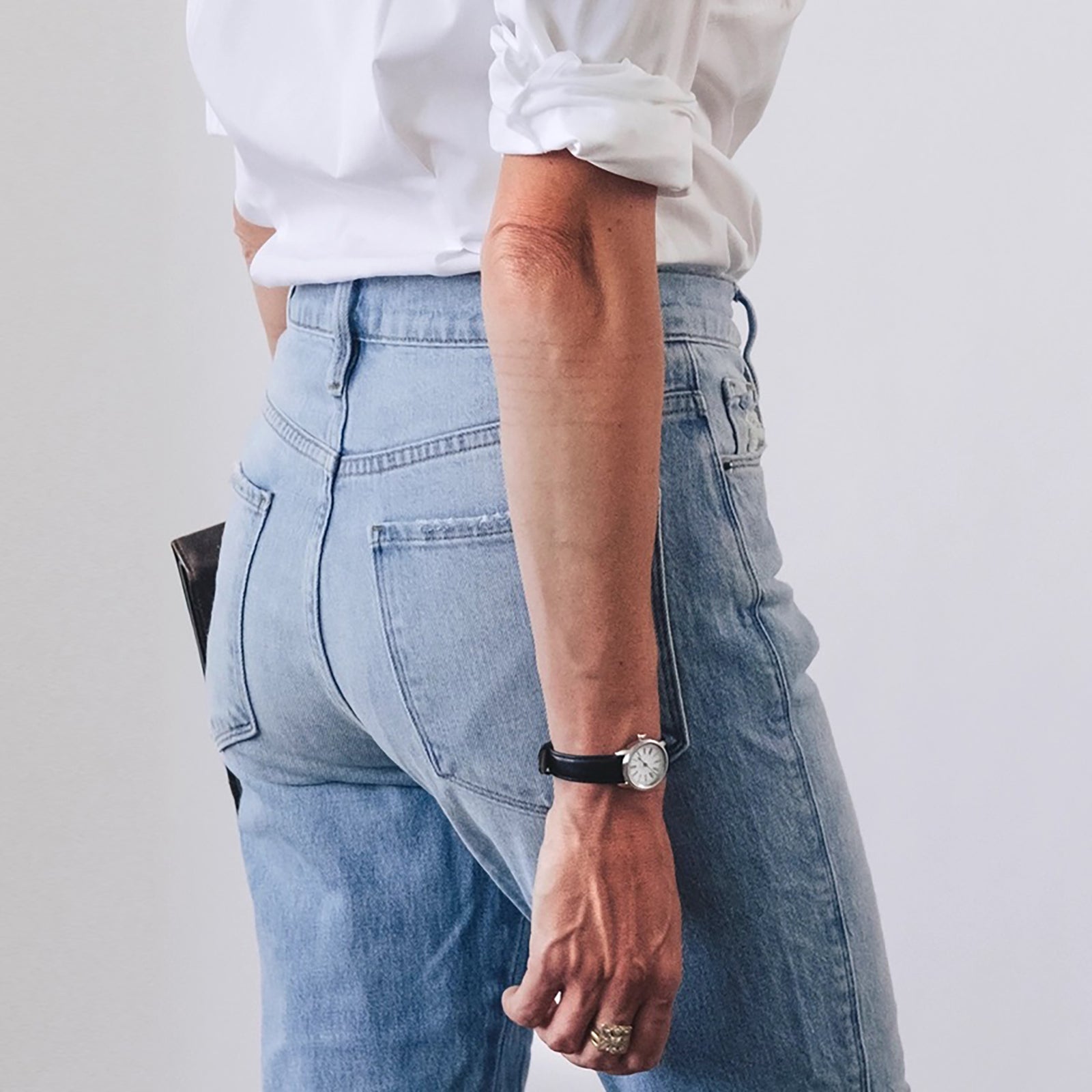 A wristwatch with a silver case and a black leather strap, featuring a white dial with black Roman numerals and blue teardrop-shaped hands.