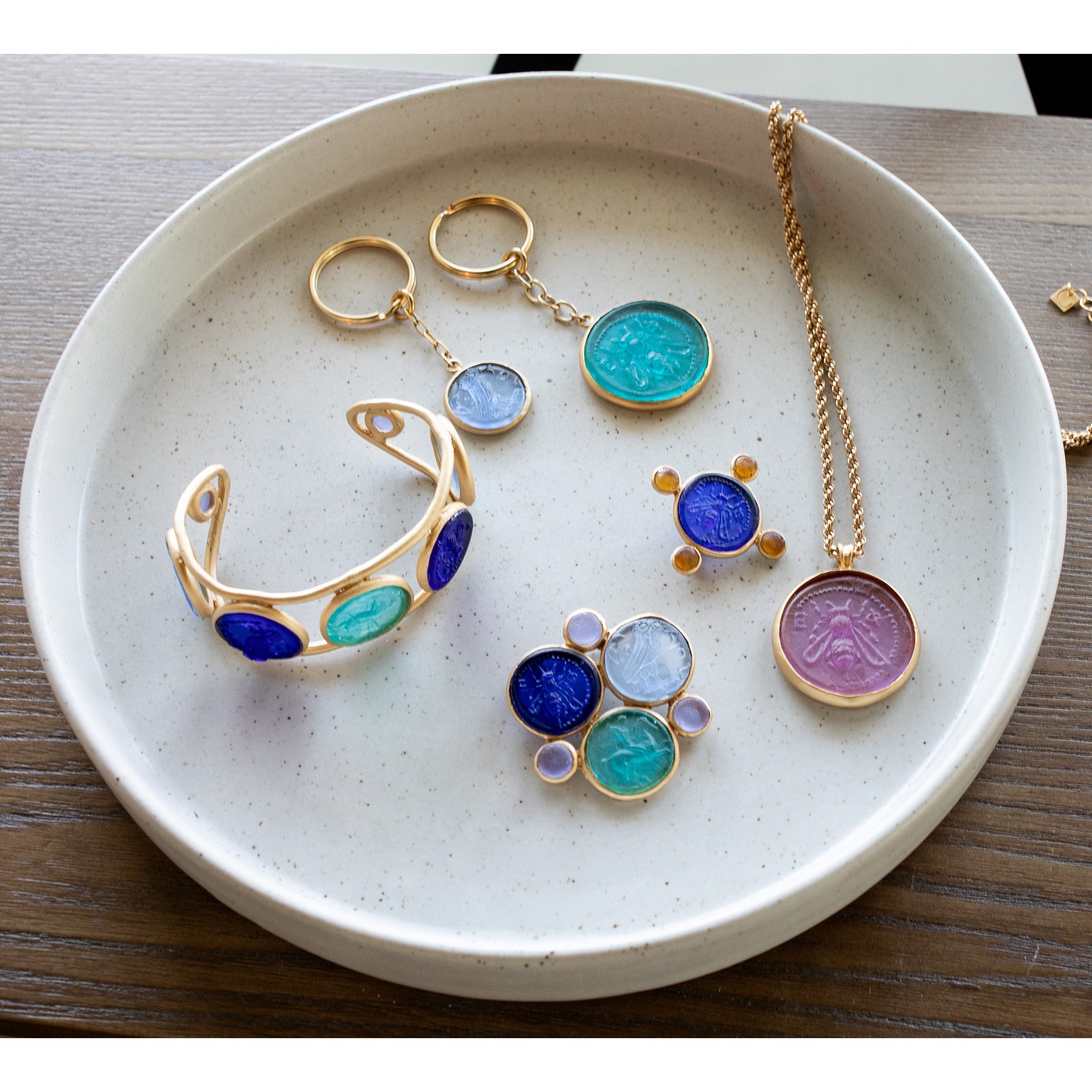 A gold key ring with a sky-blue toned handcrafted glass coin attached to it.