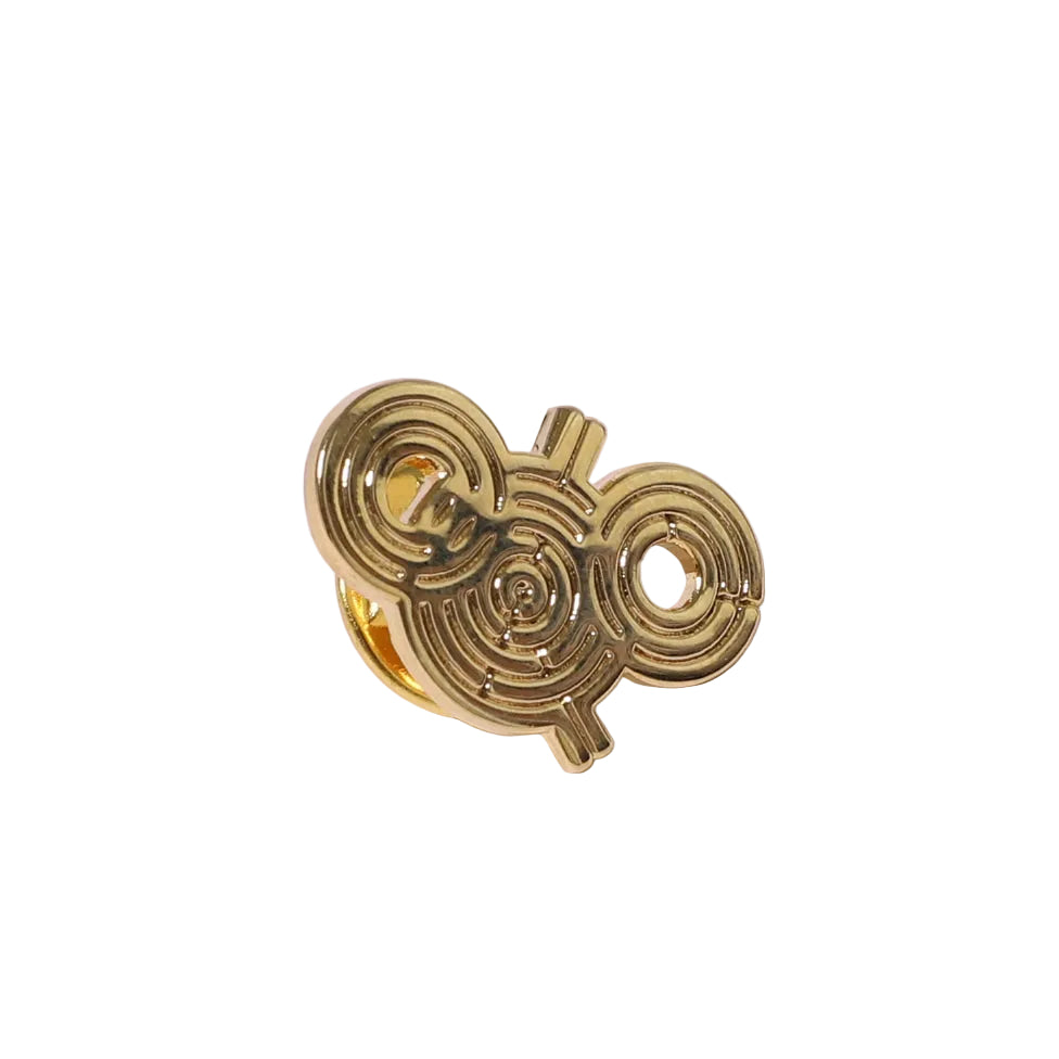 Gold pin with a unique spiral design on a white background