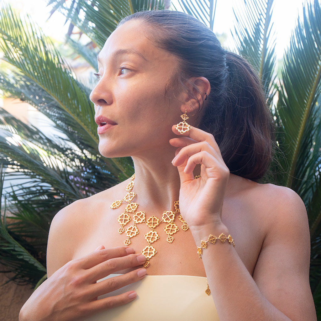 Woman wearing gold jewelry with a tropical background