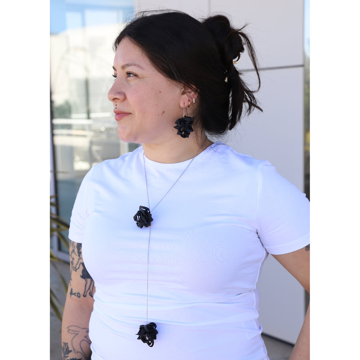 Woman wearing a white top with black floral jewelry outdoors
