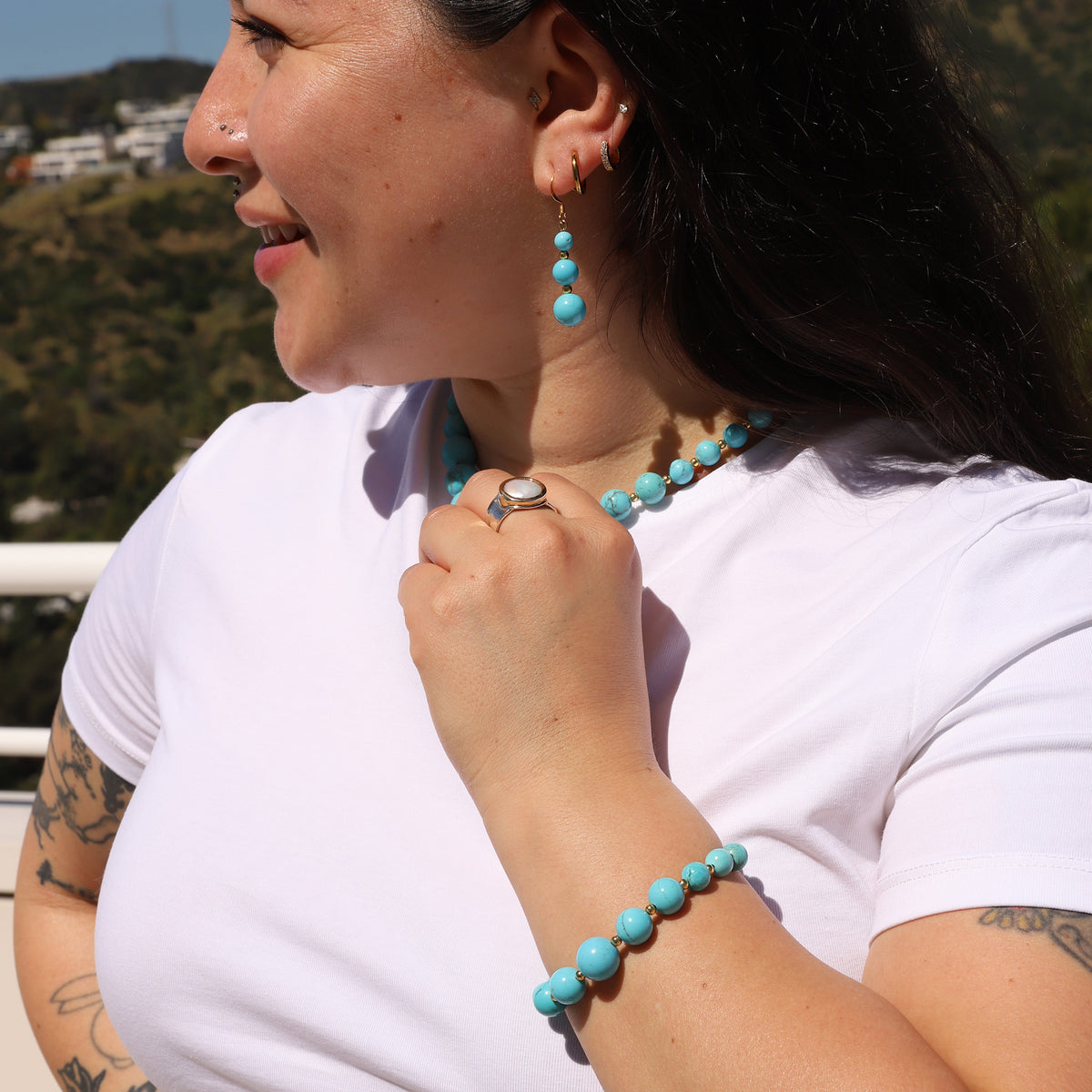 Woman wearing turquoise jewelry outdoors with a scenic background