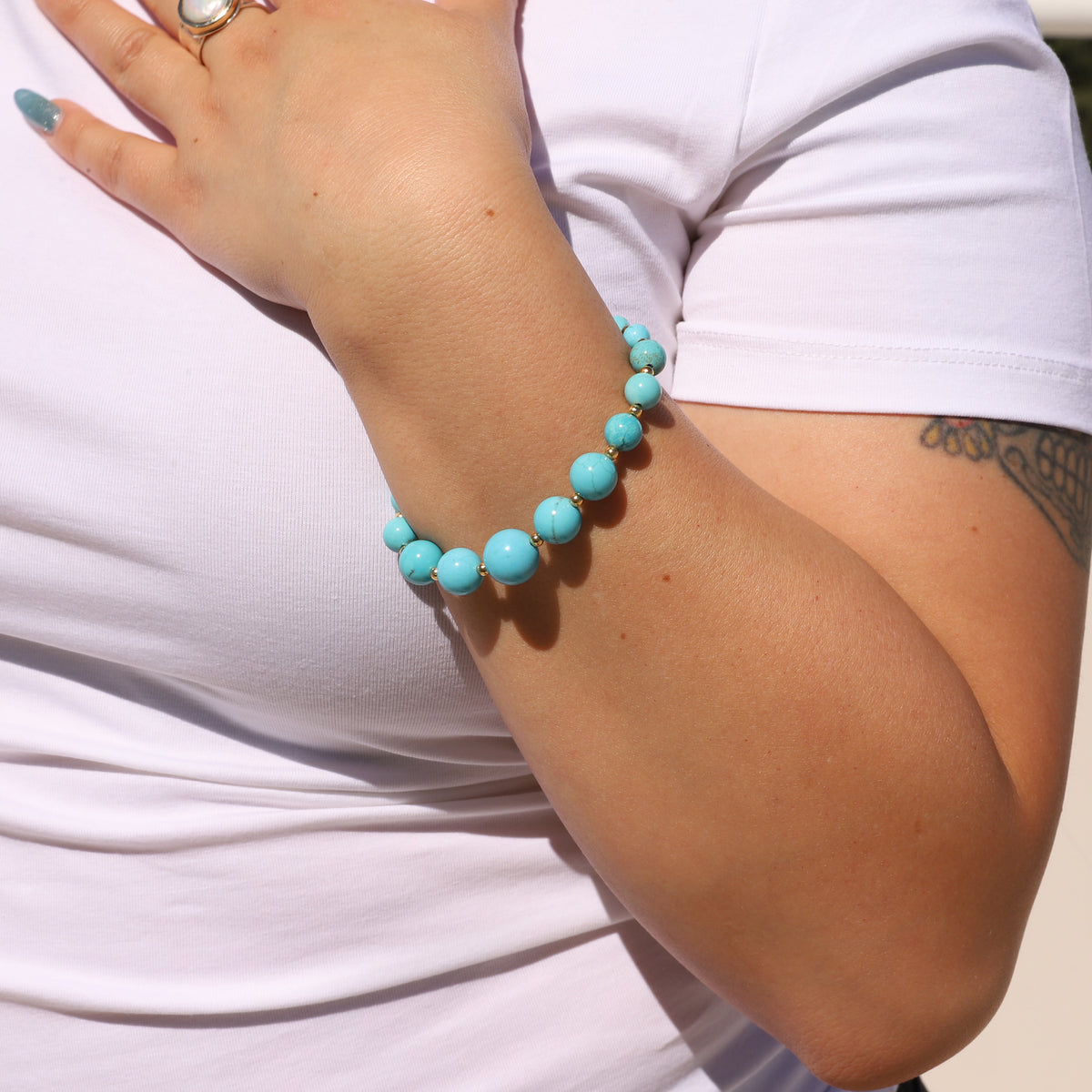 Turquoise beaded bracelet on a person's wrist with a white background